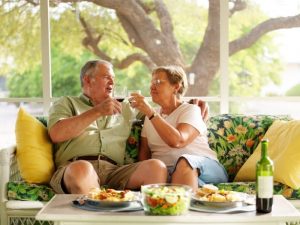 Senior couple smiling and drinking on couch