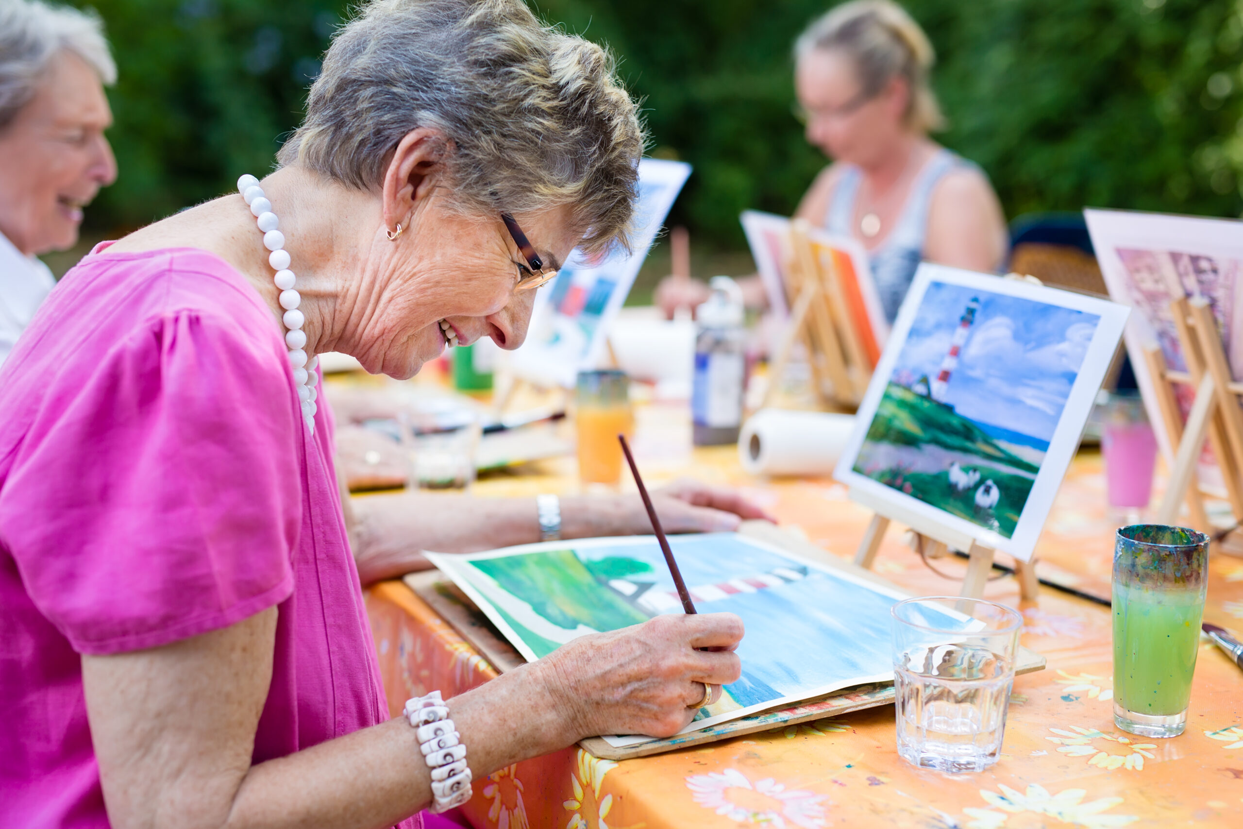 Elderly woman painting a picture outdoors