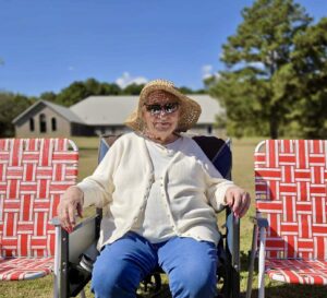 Elderly woman sitting outside in a lawn chair