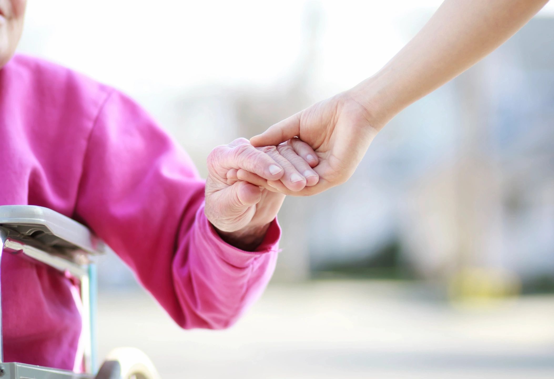 Elderly woman holding hands with caregiver