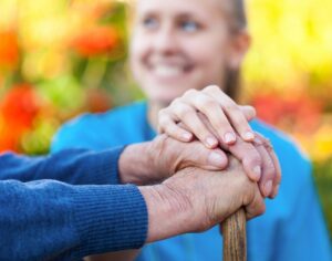caregiver and elderly person holding onto cane