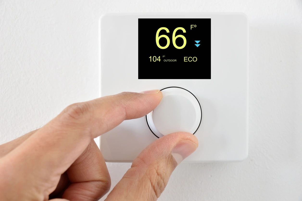 person adjusting temperature on thermostat